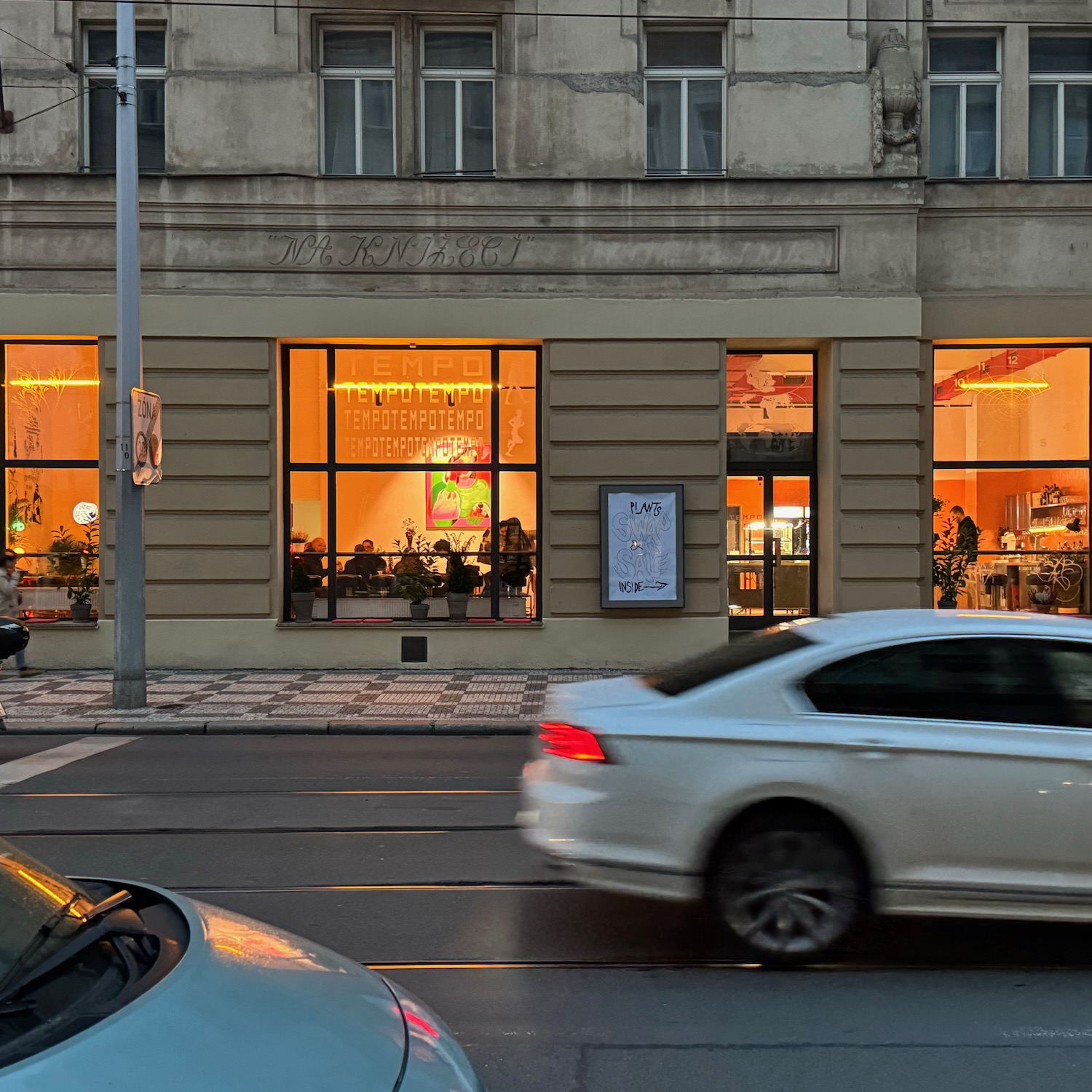 Fasáda prostoru Tempo na Nádražní ulici — osvětlená kavárna a galerie s nápisy TEMPO ve výlohách